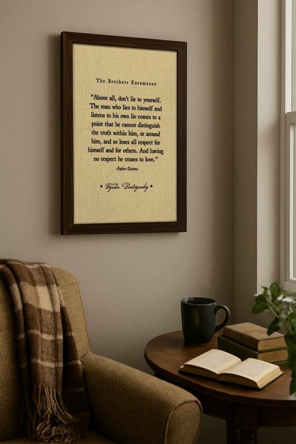 Canvas print of Dostoyevsky’s quote is mounted above a wooden side table with books, a ceramic mug, and a beige armchair with a brown plaid blanket.