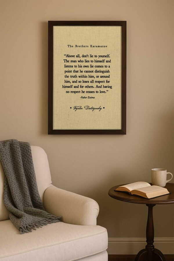 Minimalist reading nook with a cream wall and armchair, wooden side table with an open book and mug, and framed Fyodor Dostoyevsky quote on the wall.