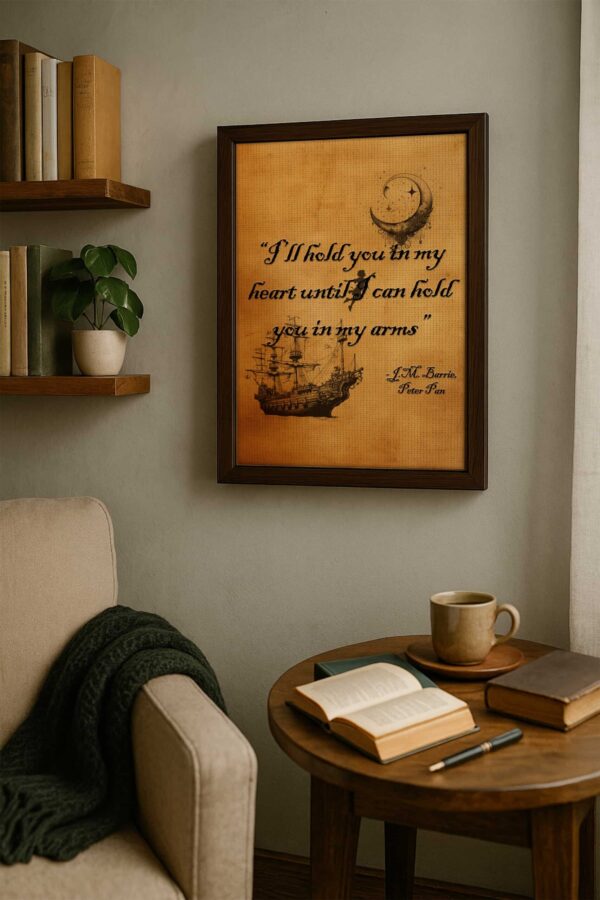 Peter Pan quote print in a wooden frame displayed above a soft gray chair with a green blanket, surrounded by books and a coffee mug on a round wooden table.