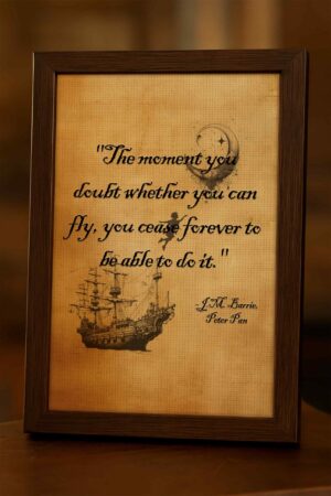 Dark wood framed print featuring Peter Pan quote in a dimly lit room with golden tones and a softly blurred background.
