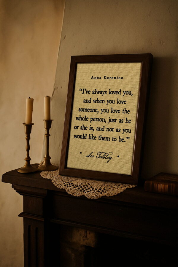 The framed Tolstoy quote sits on a vintage fireplace mantel beside two brass candlesticks and a lace doily. The warm light and antique setting evoke a cozy, old-world atmosphere.