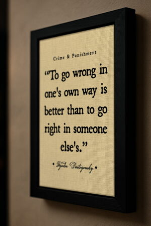 Angled view of Dostoyevsky quote wall art in a black frame, mounted on a neutral-colored wall with side lighting that highlights the textured canvas and serif font.