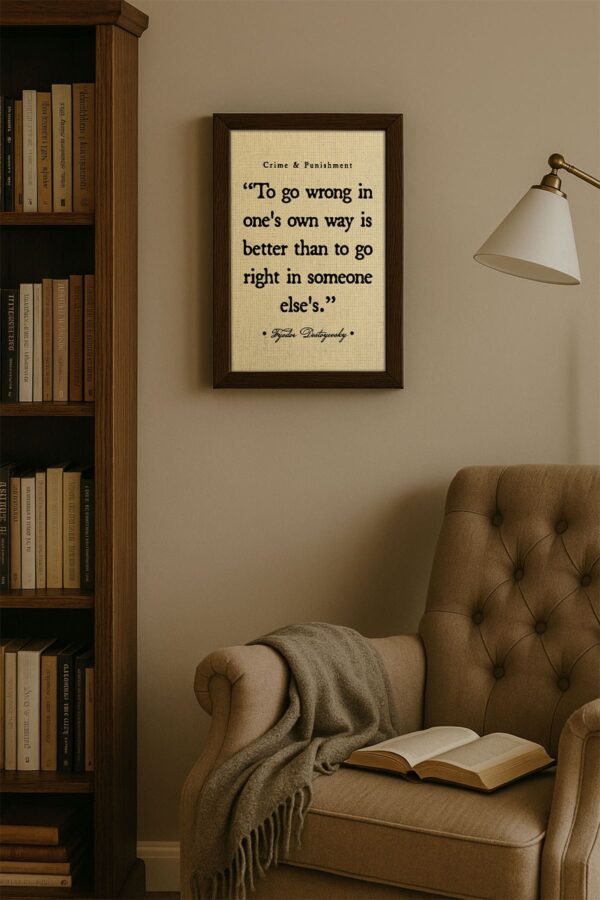 Wall art of a Dostoyevsky quote in a dark wood frame hanging above a tufted reading chair and beside a bookshelf, creating a cozy, bookish corner with soft ambient lighting.